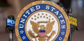 US Senate emblem with microphones in background.