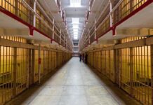 Long hallway with prison cells on both sides.