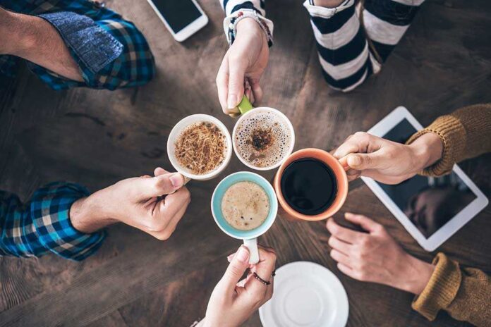 1143280904 featured image Hands holding different mugs over table.