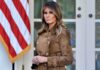 Woman in brown coat near American flag.