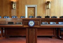 Empty U.S. Senate hearing room with wooden furniture.