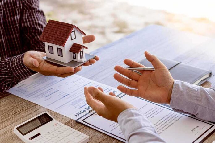 2050679492 featured image Two people discussing real estate contract with model house