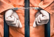 Hands cuffed in front of prison bars