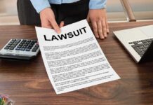 Person holding lawsuit document at desk with laptop