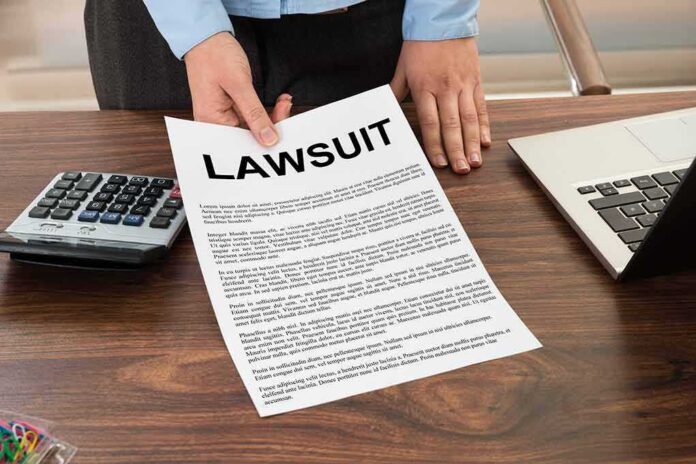 276644054 featured image Person holding lawsuit document at desk with laptop