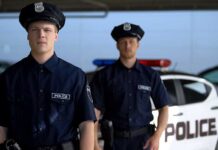Two police officers standing near patrol car