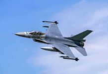 Jet fighter flying through clear blue sky.