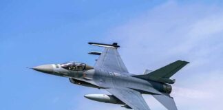Jet fighter flying through clear blue sky.