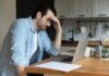 Man stressing over work on laptop at kitchen table