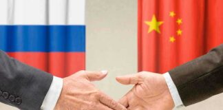 Handshake in front of Russian and Chinese flags