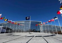Flags outside NATO headquarters building under clear blue sky