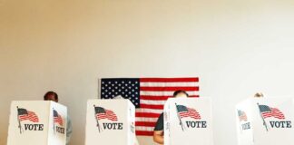 People voting in booths with American flag background