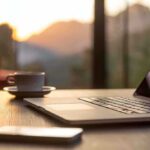 Laptop, coffee cup, and phone on wooden table