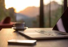 Laptop, coffee cup, and phone on wooden table