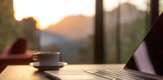 Laptop, coffee cup, and phone on wooden table