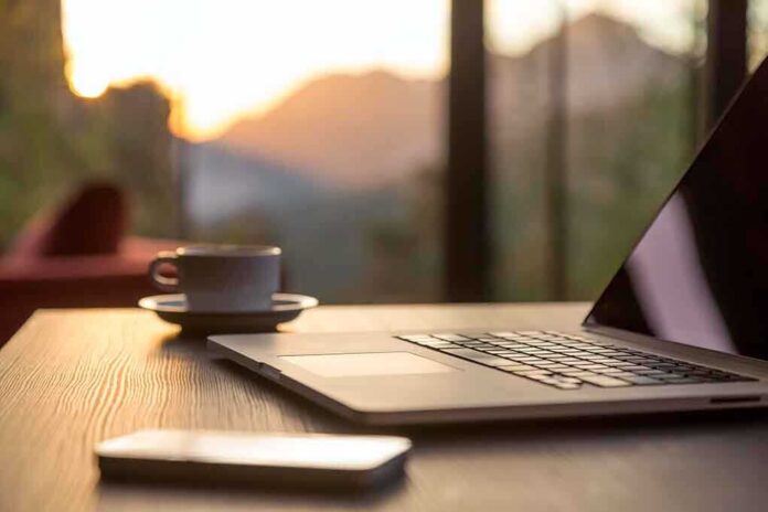 Laptop, coffee cup, and phone on wooden table