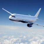Airplane flying above the clouds in blue sky