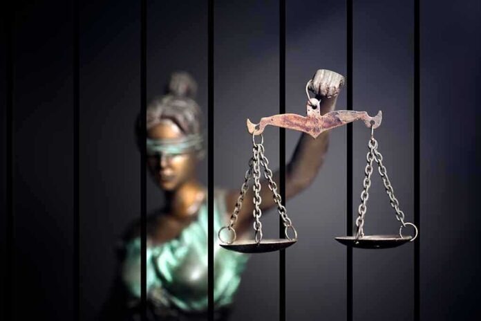 562957564 featured image Blindfolded Lady Justice statue holding scales behind bars