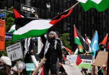 Protesters with flags and signs one holding a megaphone