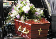 Coffin with flower arrangement in a hearse