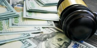 Gavel and hundred dollar bills on table