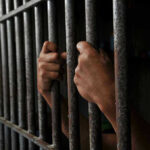 Hands gripping jail cell bars