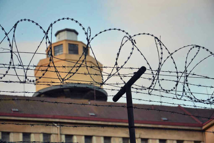 356278409 Barbed wire in front of a prison tower