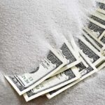 Hundred dollar bills partially buried in white sugar