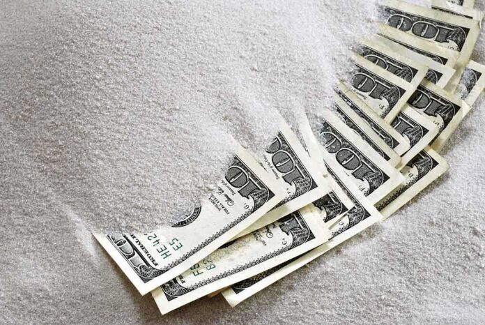 shutterstock_20529419.jpg Hundred dollar bills partially buried in white sugar
