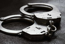 Close-up of metal handcuffs on a dark surface