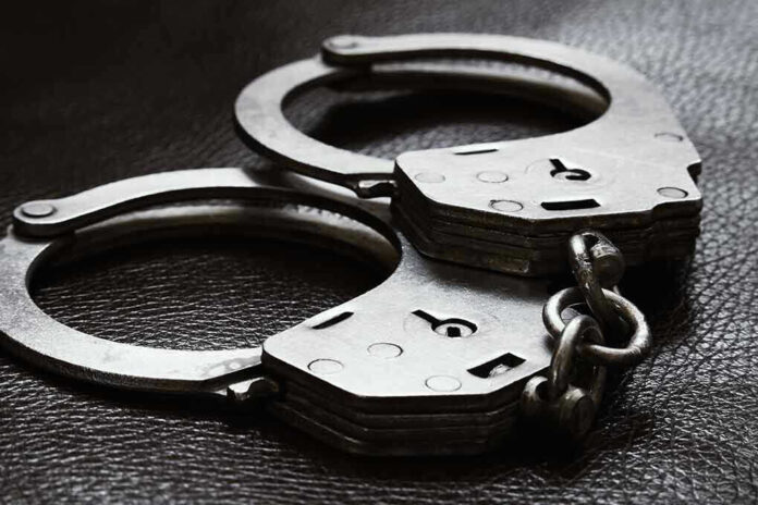 2385593779 Close-up of metal handcuffs on a dark surface