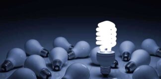 A bright energy-efficient light bulb surrounded by traditional bulbs
