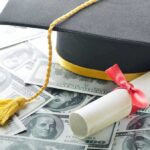 Graduation cap and diploma resting on a pile of money