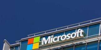 Microsoft logo on a modern corporate building against a blue sky