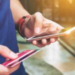 Social Media Trends DRAIN Wallets – Hidden Trap! Person holding a smartphone and a credit card, preparing for a digital transaction