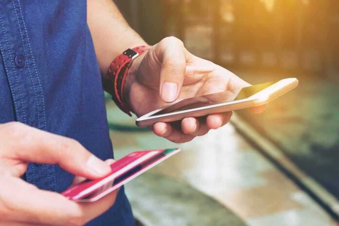 Person holding a smartphone and a credit card, preparing for a digital transaction
