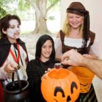 Children in Halloween costumes collecting candy from a house