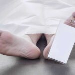 Feet of a deceased person covered by a white sheet with an identification tag