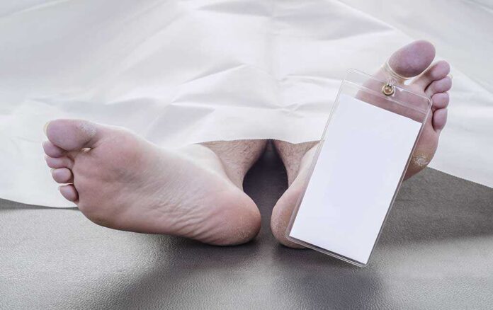 Feet of a deceased person covered by a white sheet with an identification tag