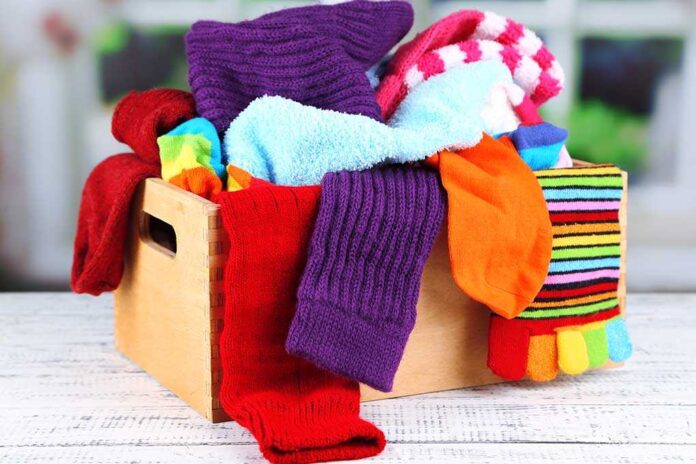 A wooden basket filled with various colorful socks in a disorganized manner