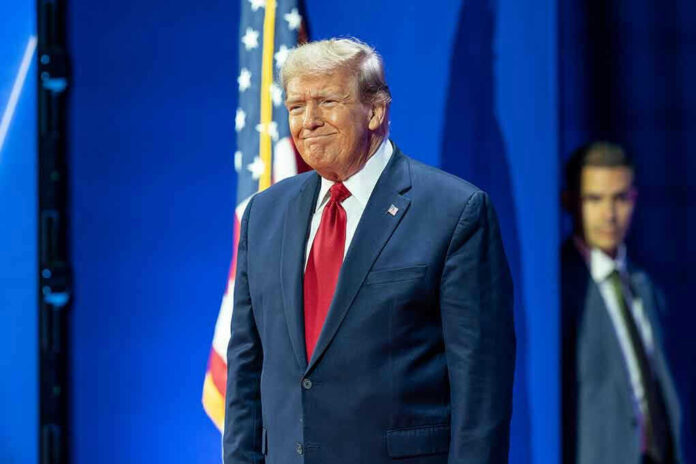 Man in suit next to American flag.