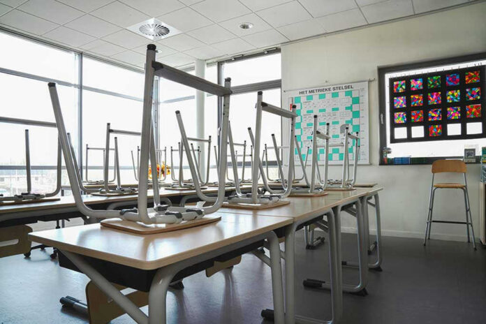 Empty classroom with chairs on top of desks.