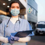 Nurses ABANDON Hospitals to Join Anti-ICE Protests – Blackout Fury! Nurse in scrubs and mask outside hospital holding clipboard.