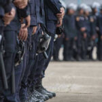 1,000 Agents Descend on City — HIGH ALERT! Line of police officers in uniform in formation.