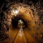 Devastating Mine Collapse – 200+ Buried Alive! Dimly lit underground tunnel with rail tracks and rocky walls