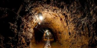 Dimly lit underground tunnel with rail tracks and rocky walls