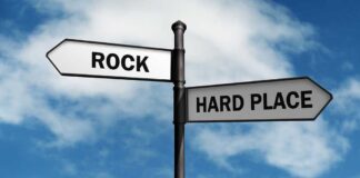 Directional signpost with ROCK and HARD PLACE labels against a blue sky