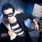 Masked Robbers Execute TEN HOUR Terror Siege A masked thief in a striped shirt holding a bag while emerging from a bank vault