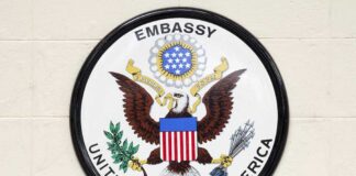 Seal of the United States Embassy featuring an eagle and the American flag