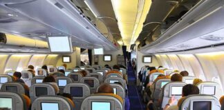 Passengers EXPLODE After Airlines Implements New Policy Interior view of an airplane with passengers seated and using in-flight entertainment screens